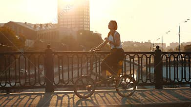 Red haired woman riding a bicycle on background sunlight in city