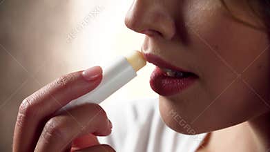 Lips care. Woman applying protection lip balsam closeup