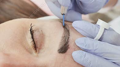 Permanent makeup. Permanent tattooing of eyebrows. Cosmetologist applying permanent make up on eyebrows- eyebrow tattoo.