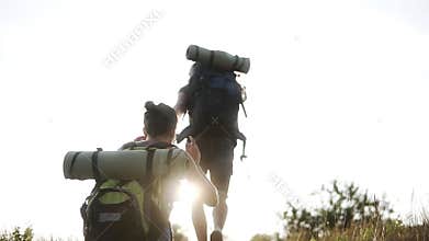 Backside footage of a young couple hiking together. Climbing the top of the hill. Happy, smiling, enjoying. Friendship