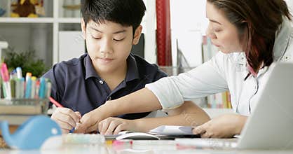 Cute asian mother helping your son doing your homework .