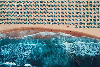 Aerial top view on the beach. Umbrellas, sand and sea waves