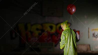 Standing back gloomy dwarf in cloak with balloon in hand turns face at camera