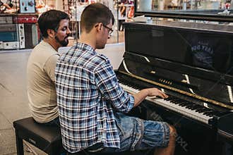 Two man playing a public piano installed in the hall inside St.