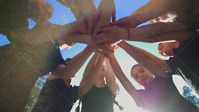 Group of school kids performs sports motivational greeting with hands on playground of yard football at sunny day