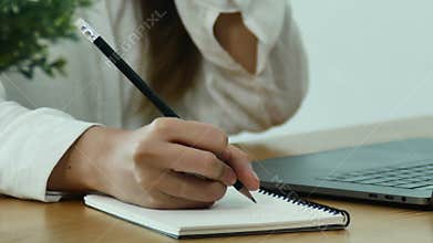 Beautiful young smiling asian woman working on laptop while sitting in a living room at home.