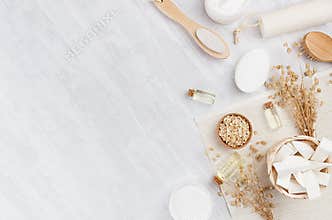 Traditional natural rustic spa white cosmetics products and beige bath accessories on light wood background, border, top view.