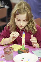 DIY Christmas candle. Girl paints a wax candle.