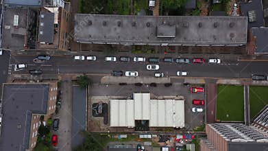 Aerial birds eye overhead top down tracking view of car giving way to oncoming traffic in narrow town street. London, UK