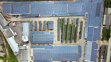 Aerial view of blue photovoltaic solar panels mounted on building roof for producing clean ecological electricity