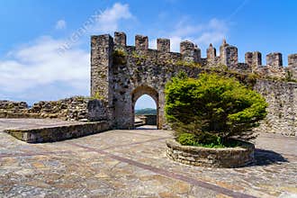 Medieval castle with stone wall and arched entrance gate in sunny day. Suances Santander