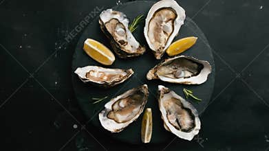 Oysters with lemon on black plate