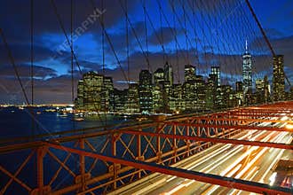 Brooklyn Bridge with fast moving traffic on the road at Twilight with Lower Manhattan in the background, New York, USA America