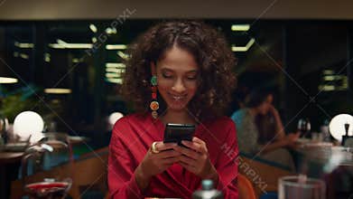 Sexy girl surfing mobile phone on dinner date. Woman sitting at restaurant table
