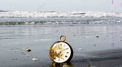 An alarm clock on the sand in front of the sea waves