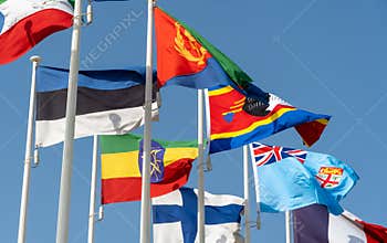 Close up of world flags flying in a row outside of expo center in 2020 waving on blue sky background Ethiopia, Finland, Eswantini