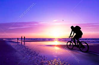 Mountain biker on beach and su
