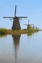 A row of windmill from front to back with beautiful river water reflection in vertical view, Kinderdijk, Netherlands