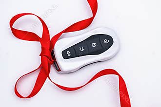 Concept and gift idea. Flat lay smart car key with a red gift ribbon on a white background. Electronics, spare parts and car