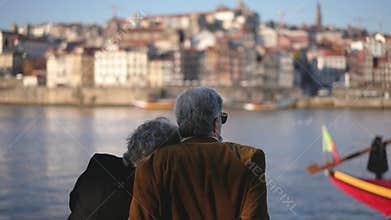 Traveling family couple of old people sitting at Duero river quay in Porto.
