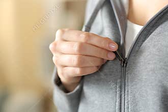 Teen hand closing zipper of gray hoodie at home