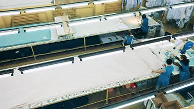 Plant workers are rolling out a large sheet of cloth