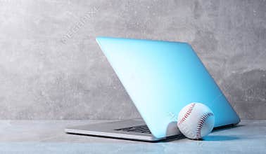 Baseball ball and grey laptop on grey background. Online workout concept