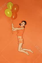 Caucasian woman being lifted into air by balloons.