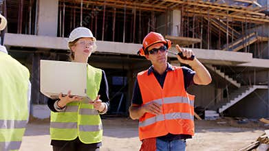 Foreman middle-aged and his assistant lady walking in front of the camera with a laptop to analyzing the plan of