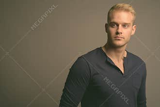 Young handsome man with blond hair against gray background