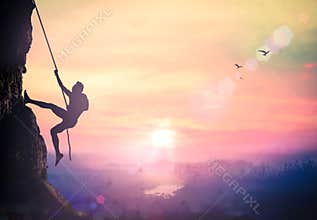 Silhouette of Determined Rock Climber Ascending Steep Cliff Against Vibrant Purple Sunset Sky