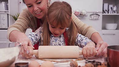 Little girl help her mother stretch the dough - close up