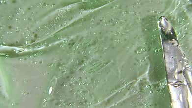 Green liquid cream, cosmetic gel fluid, smear motion on a surface. Beauty skincare product sample. Top view. Slow motion