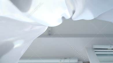 Bright morning sun in the open window through the curtains. Abstract white waving curtain in white bedroom apartment.