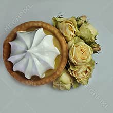 Cake with white cream in a basket of dough Blooming yellow roses On a white background Close-up
