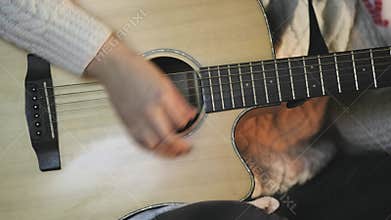 Closeup of musician woman playing guitar near bonfire at night on background of blurred city lights.