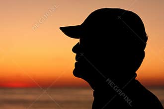 Silhouette profile of man wearing baseball cap
