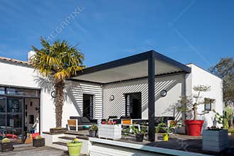 Trendy outdoor patio pergola. garden lounge, chairs, metal grill surrounded by landscaping