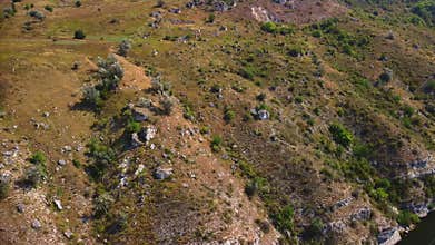 Drone closing up on a mountainside, rocky hill with the cliff.