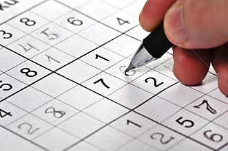 Close-up a pencil in hand and puzzle Sudoku.