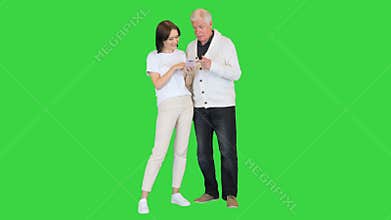 Daughter shows pictures on a mobile phone to her old father on a Green Screen, Chroma Key.