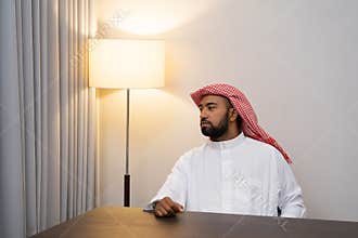 Arabs in turbans look to the side while sitting behind a desk