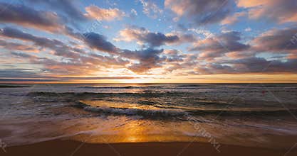 Ocean beach and golden sunrise. Sea sand and washing waves on the coast.