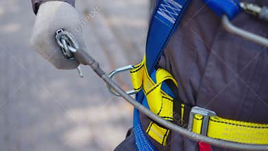 Industrial climber puts on equipment for high-altitude work. On climber s belt carabiners.