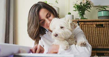 Caucasian woman drawing working from home and cuddling her pet dog