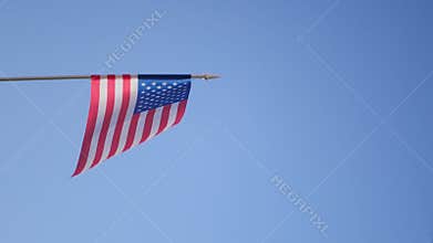 American flag waving on blue sky background.