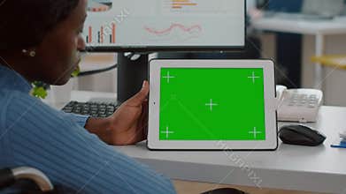 Handicapped african employee in wheelchair looking at tablet with green screen