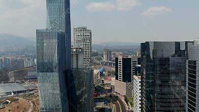 Elevated view of wide street lined by tall buildings. Drone flying high above road between modern skyscrapers. Mexico