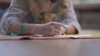 Unrecognizable man lying on floor drawing clothes sketch with pencil. Young creative Caucasian dressmaker designer