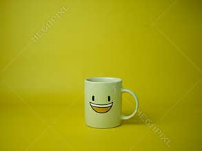 yellow coffee mug with smile emoticon icon.